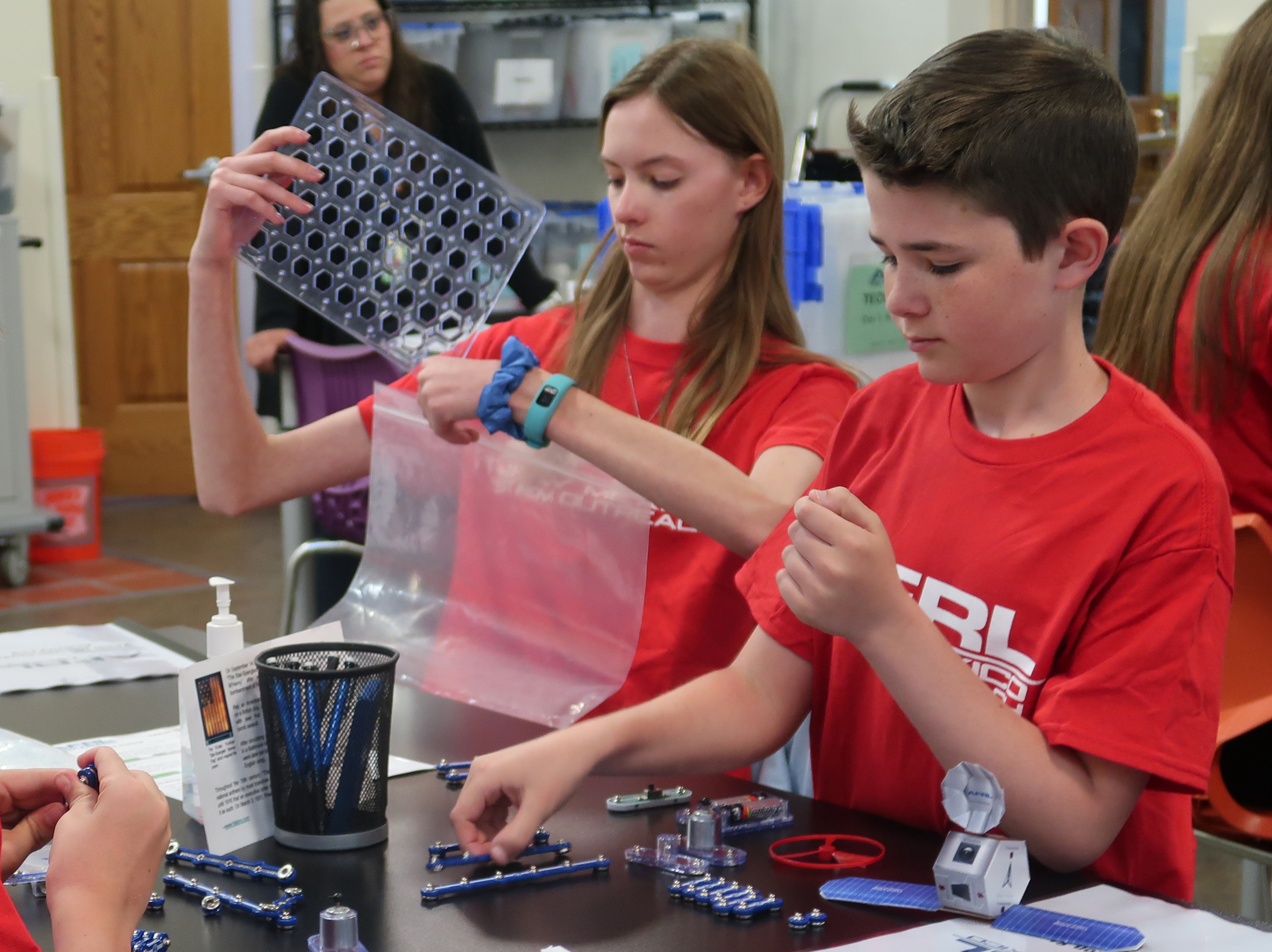 Two students using Snap Circuits, a kit that has pieces that snap together to create a flow of electricity.